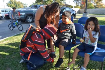 A happy Sebastian Robledo gets a new pair of shoes as brother Manuel helps put them on. Also looking on are Maria and Mom Paula Robledo 